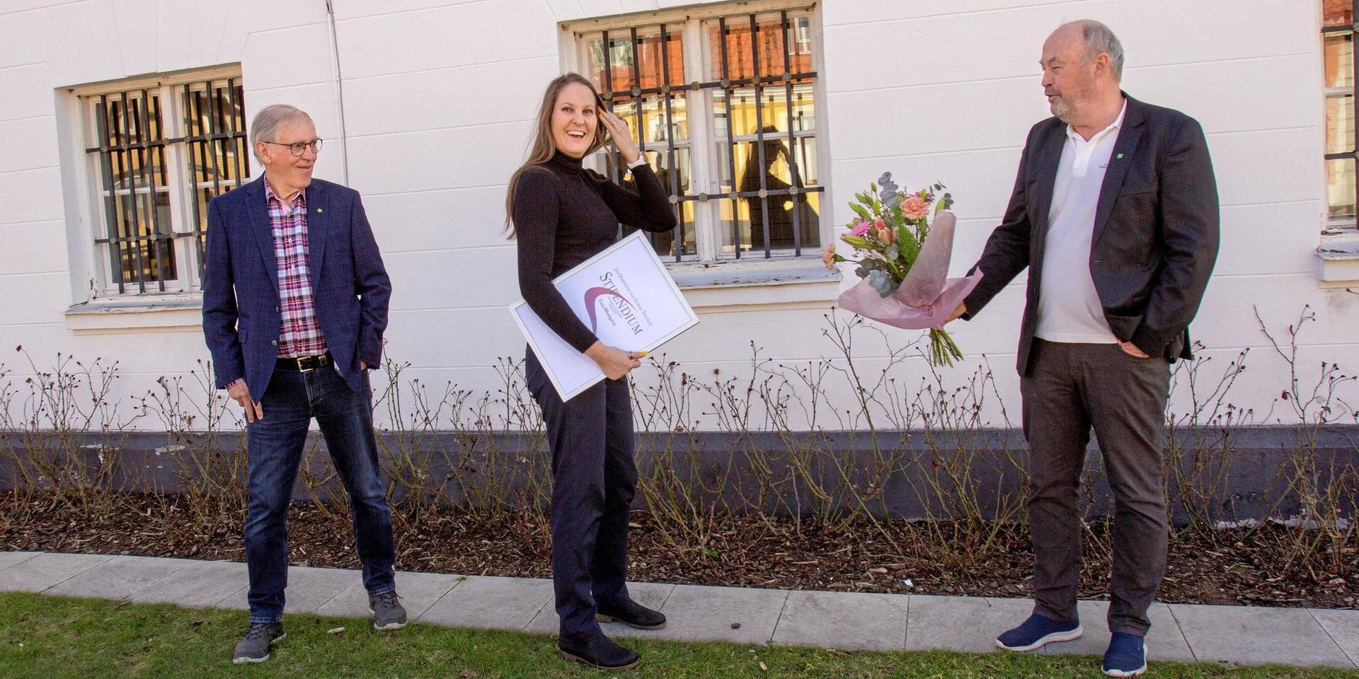Stipendieutdelning på coronatryggt avstånd. Tommy Paulison och Roy Karlsson från Gamla Laholm överräcker blomsterkvast och diplom till årets stipendiat Tina Blomberg. I priset ingår också en summa pengar.