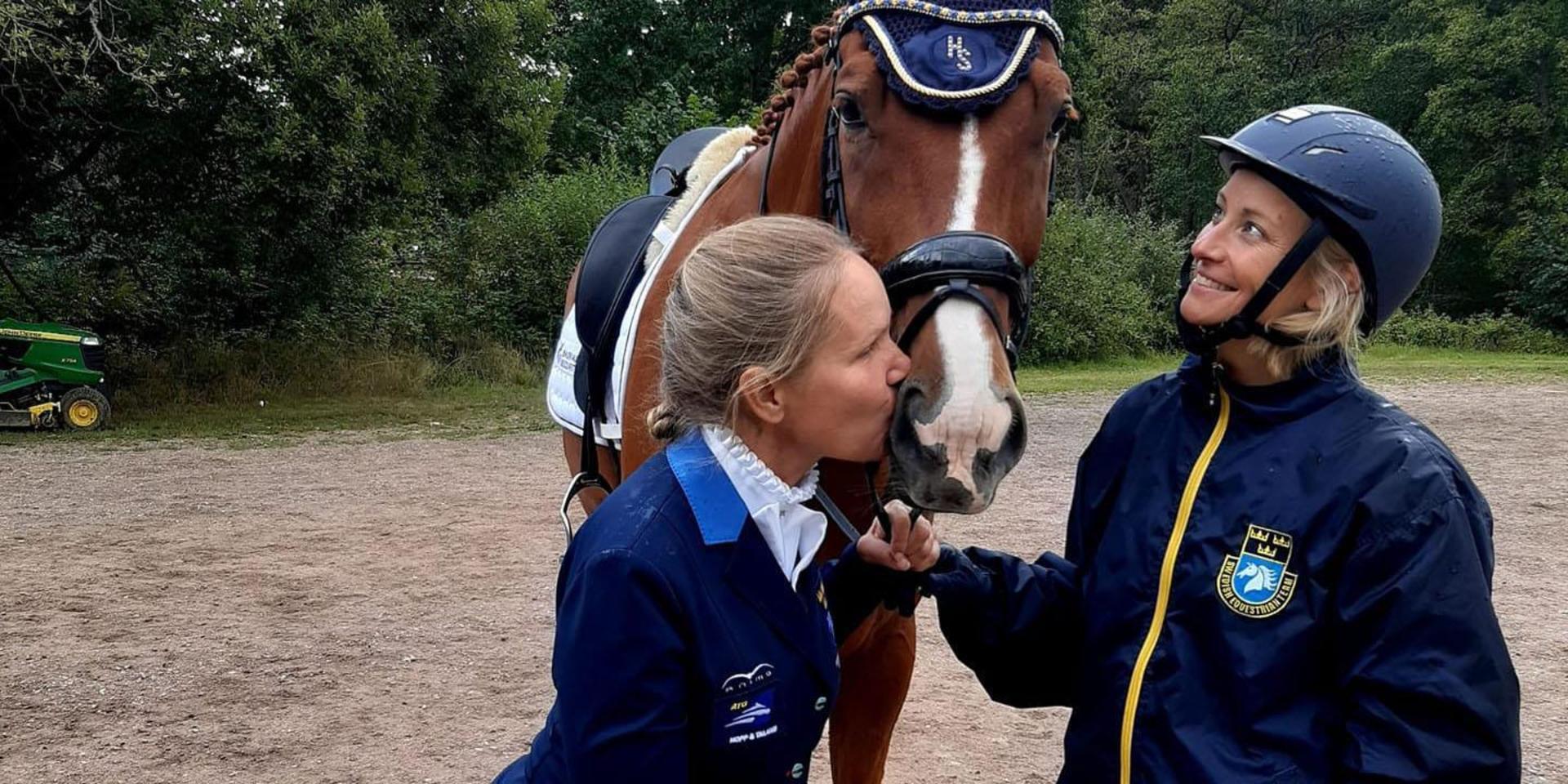 Anita Johnsson ger hästen Dear Friend en segerkyss under överinseende av groomen Sara Olsson efter SM-guldet i paradressyr.