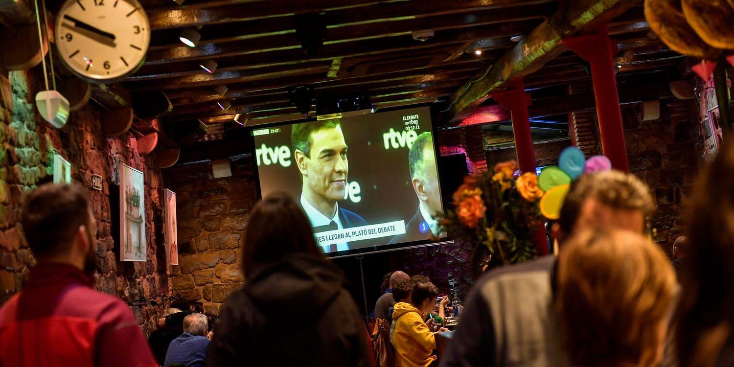 Människor tittar på den tv-sända partiledardebatten i Pamplona, Spanien.