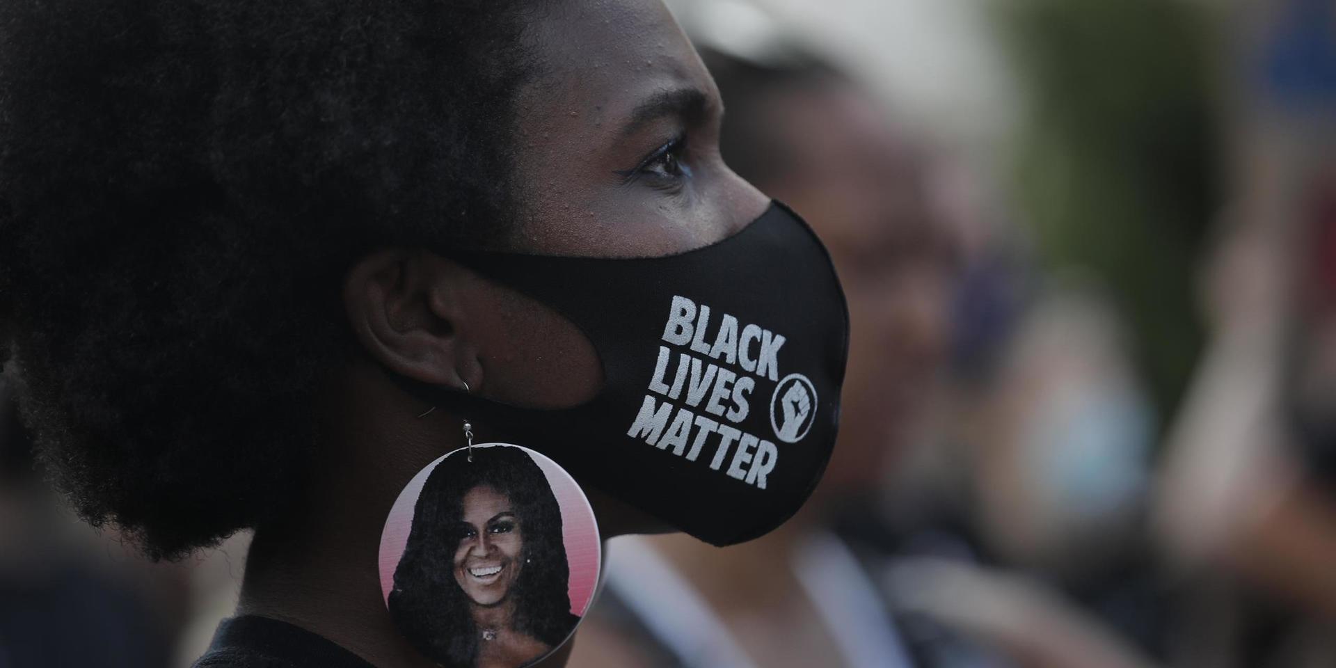 En kvinna i Michelle Obama-örhängen protesterar utanför Vita huset i Washington. Arkivbild.