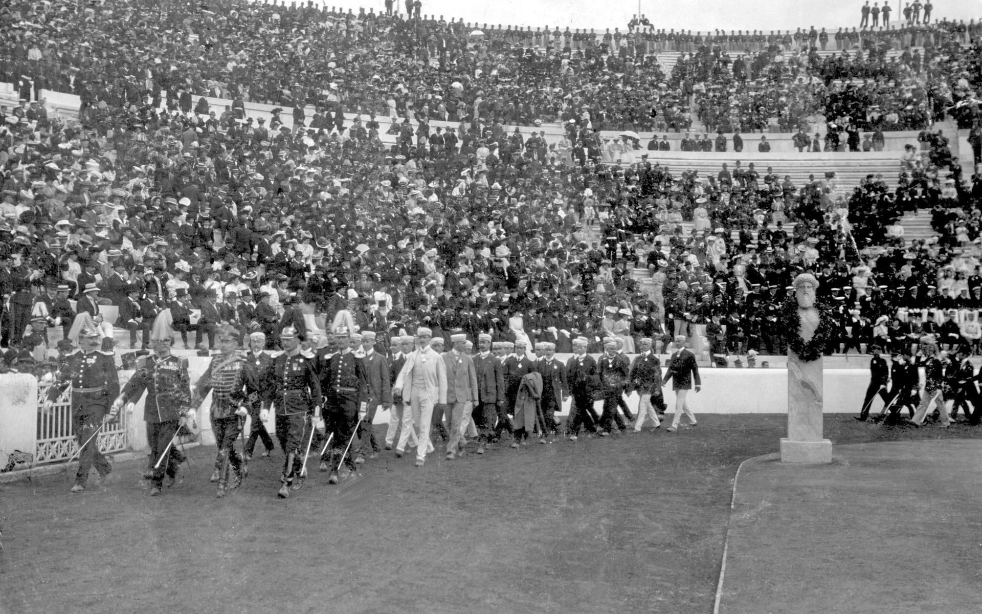 Den svenska truppen, ledd av överste Wiktor Balck, marscherar in som en av 20 nationer på stadion den soliga invigningsdagen den 22 april 1906.