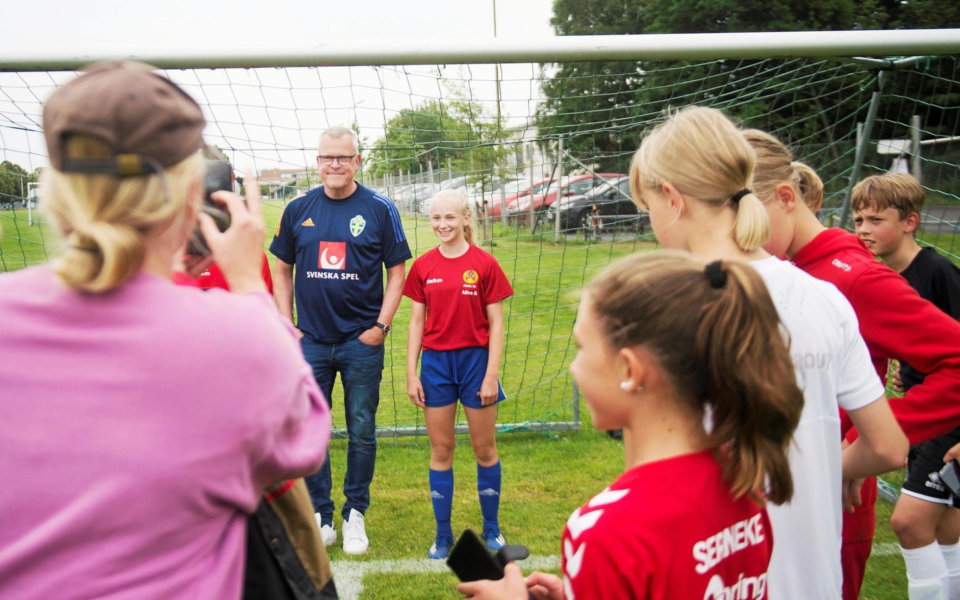 Janne Andersson ställer upp och skriver en hel del autografer när han besöker Alets fotbollsskola under sommaren. Här är det tolvåriga Alice Brogren som passar på att ta ett foto med förbundskaptenen.