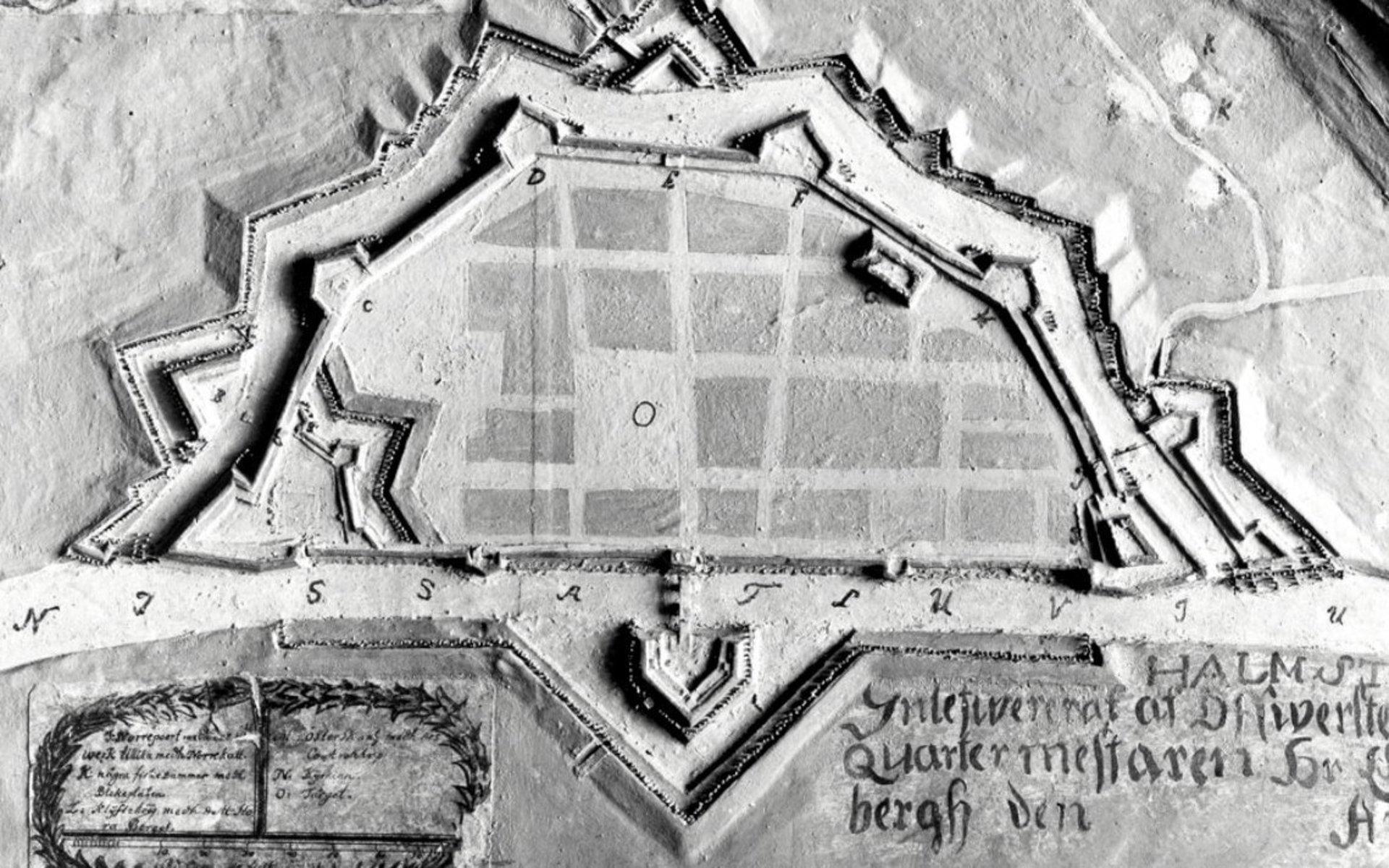Österskans 1677, enligt Erik Dahlberg, fästningsarkitekt, strateg och tecknare av stormaktstidens slott och palats. Det vita strecket är Nissan, och det lilla V:et är vallgraven – och där går alltså Österbro i dag. 