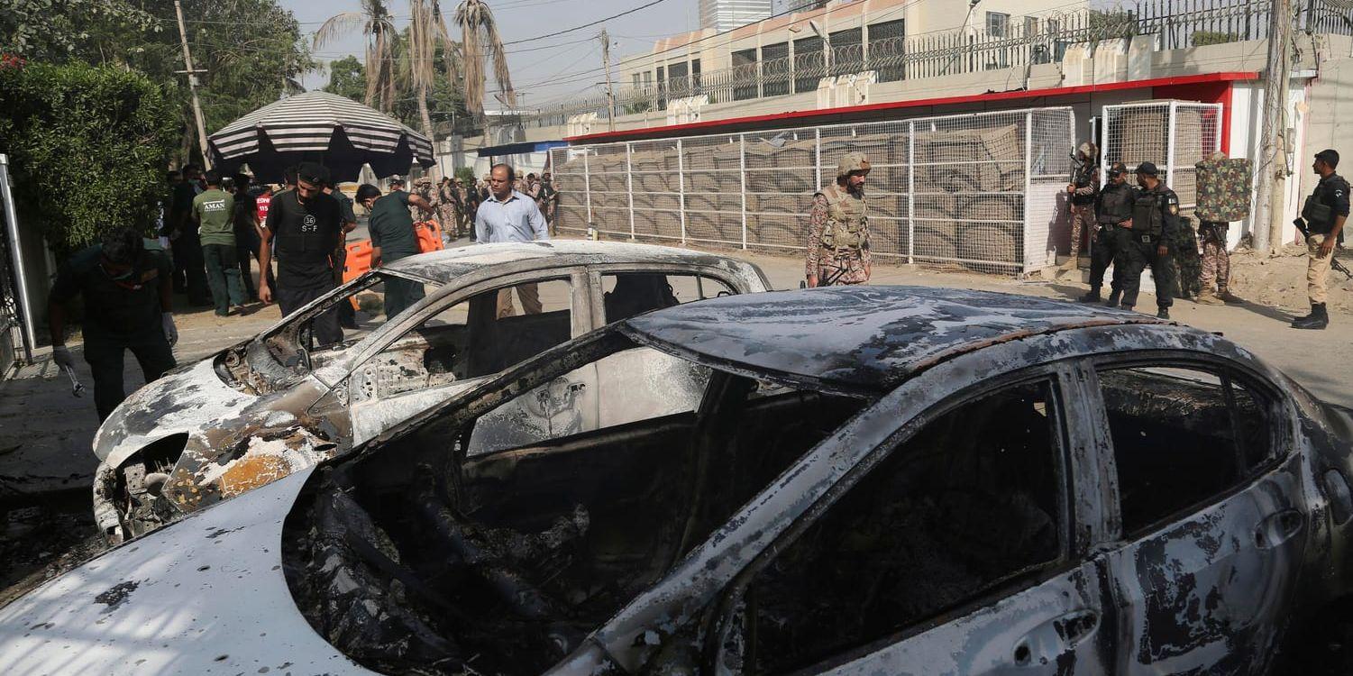 Urbrända bilar utanför Kinas konsulat i Karachi. Två poliser dödades i attacken.