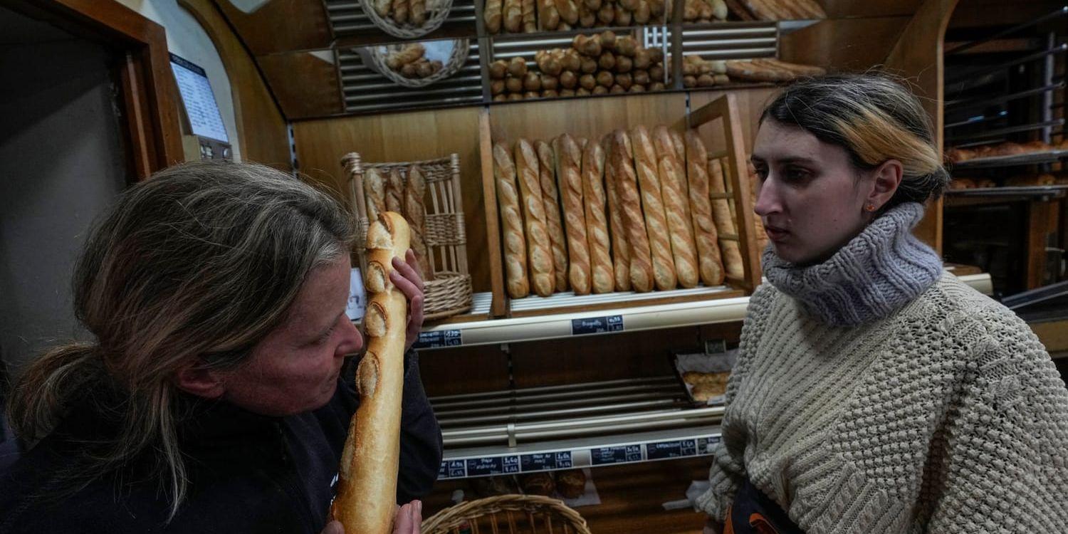 Bageriägaren Florence Poirier, till vänster, luktar på en nybakad baguette som Mylène Poirier just har tagit ur ur ugnen, på bageriet i Versailles utanför Paris.