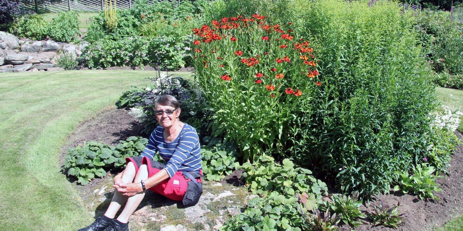 Avkopplande. På flera ställen i den stora trädgården kan man slå sig ner bland blommorna. Här sitter Sonja Andersson vid en grupp med bland annat röd solbrud.