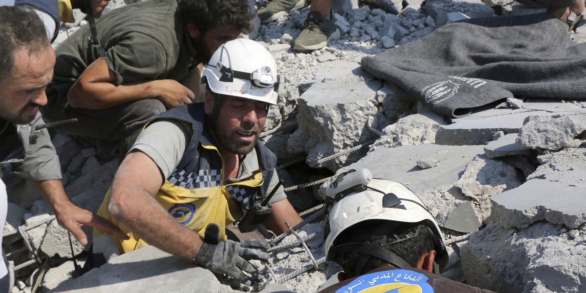Medlemmar av den syriska organisationen Vita hjälmarna arbetar vid en byggnad i byn Deir al-Sharqi som raserats i en flygattack på lördagen. Bildens äkthet har autentiserats av nyhetsbyrån AP. 