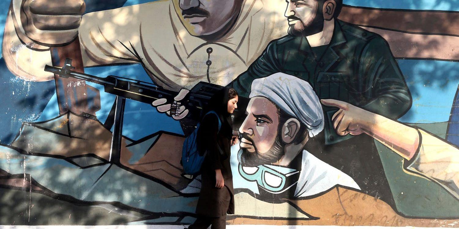 En kvinna går förbi en väggmålning som föreställer medlemmar ur den religiösa frivilligmilisen Basij och som föreställer iransk solidaritet mot landets fiender. När USA:s sanktioner nu träder i kraft är många oroliga över konsekvenserna i Iran.