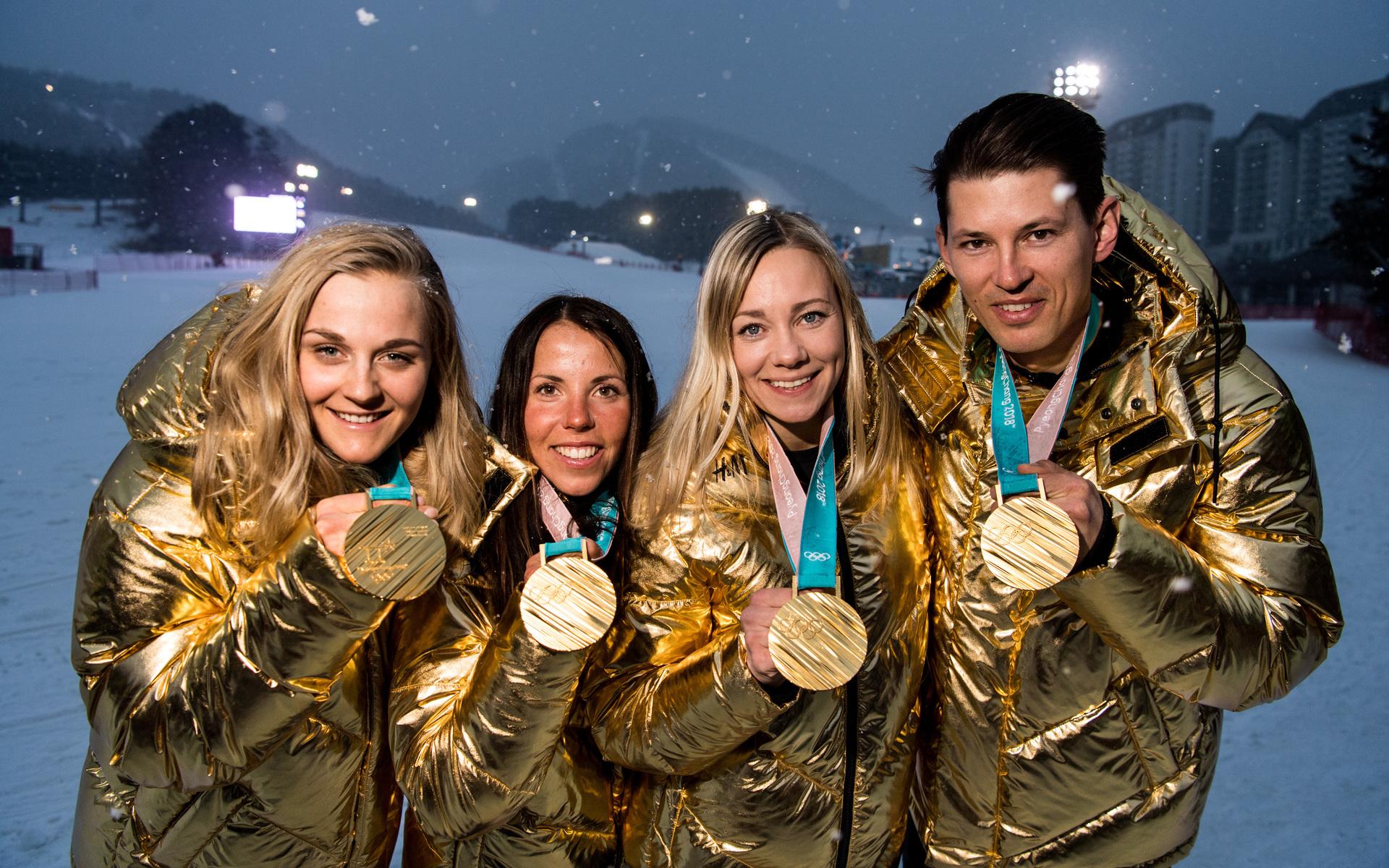 Här visar Charlotte Kalla upp guldmedaljen tillsammans med några andra guldmedaljörer från OS 2018. Stina Nilsson, Frida Hansdotter och Andre Myhrer nådde också högst upp på pallen under spelen i Sydkorea. 