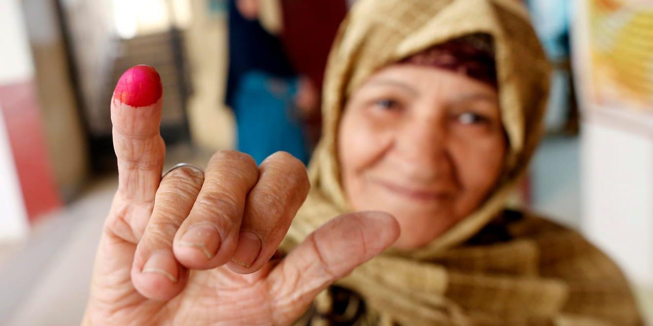 En kvinna visar upp sitt röda finger efter att ha röstat.