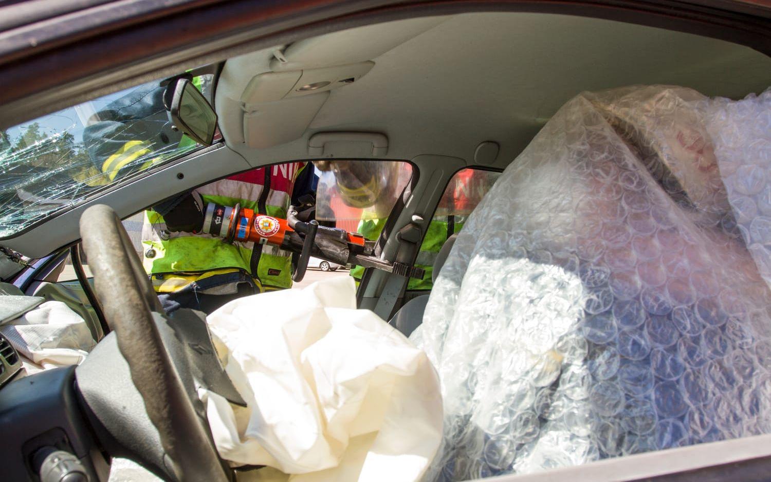 Den trafikskadade med nacksmärtor täcks över för att skydda mot glassplitter när rekryterna får prova att klippa av taket på en bil. Bild: Kenny Hjälte