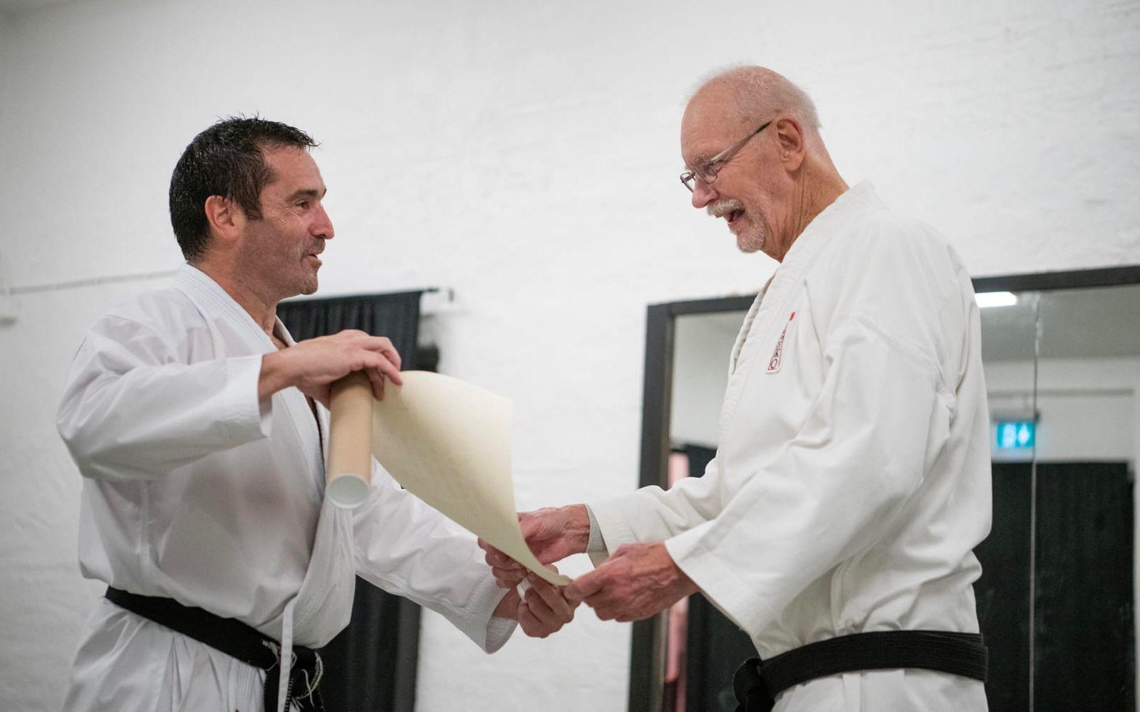 Karatenestorn Roy Andersson (till höger) i Halmstad får ta emot graderingen till åttonde dan av Scott Langley, som är teknisk chef för internationella karateorganisationen HDKI.