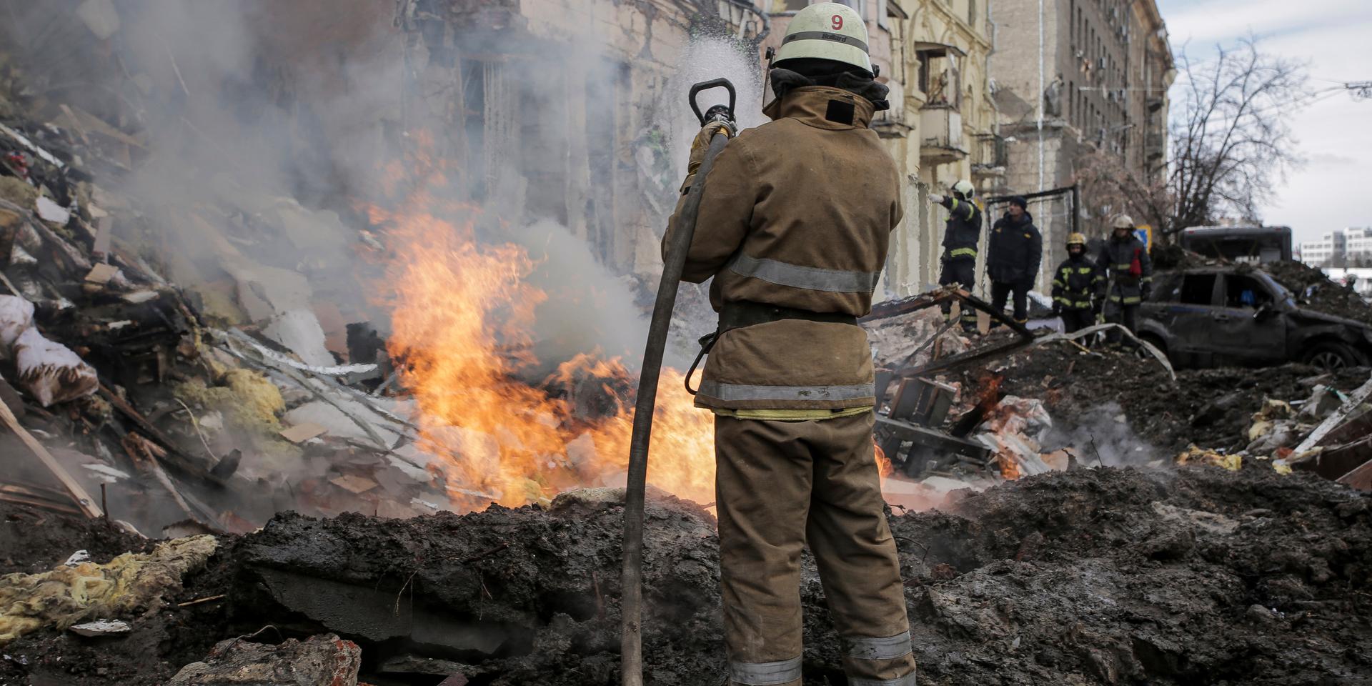 Brandmän försöker rädda ett hus i Charkiv som träffats i en robotattack.