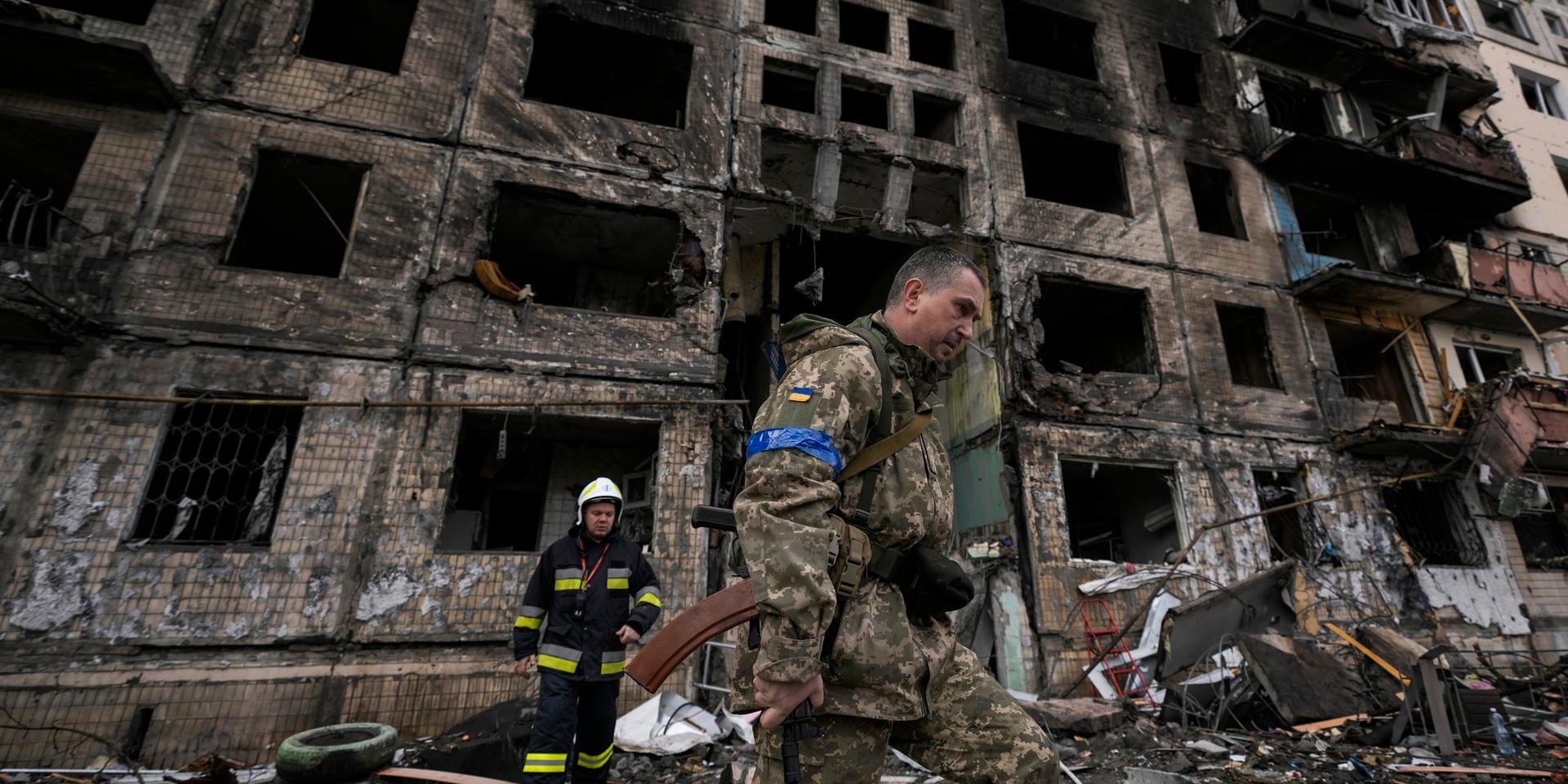 Ukrainska soldater och räddningstjänst arbetar vid bostadshuset i Kiev som förstörts i en bombning på måndagsmorgonen.