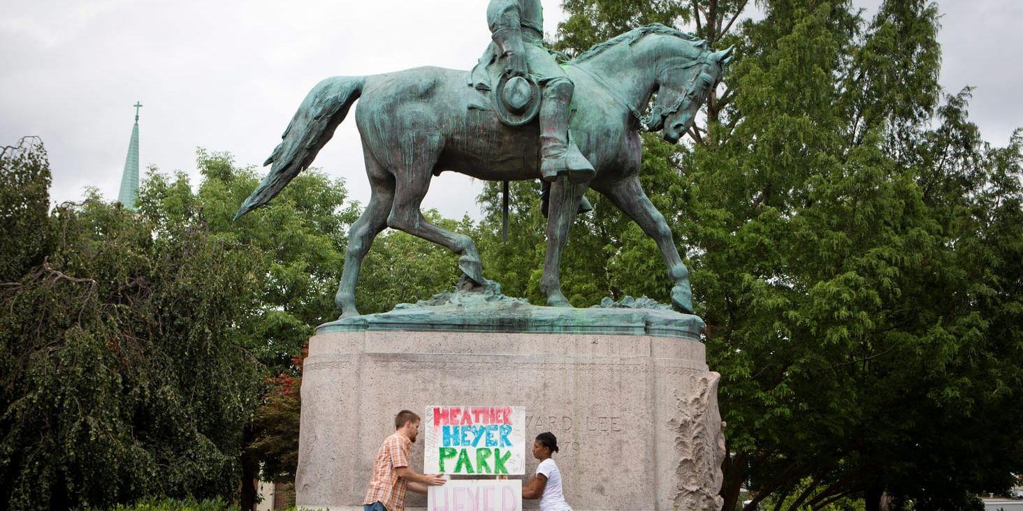Statyn på sydstatsgeneralen Robert E Lee står i Lee Park i Charlottesville, och utlöste de demonstrationer som slutade med mord i staden. På bilden har två demonstranter döpt om parken efter mordoffret: Heather Heyer Park.