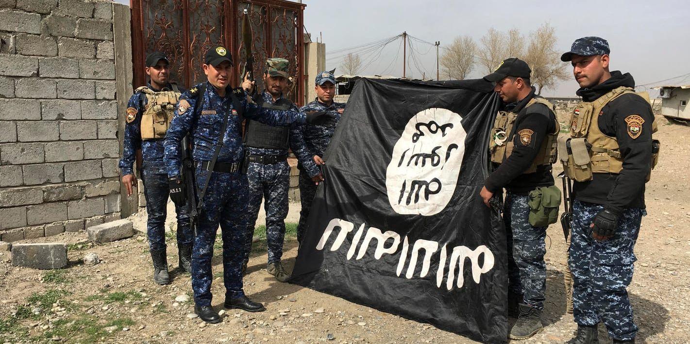 Irakisk polis med en IS-flagga som beslagtagits i samband med återtagandet av Mosul. Arkivbild.